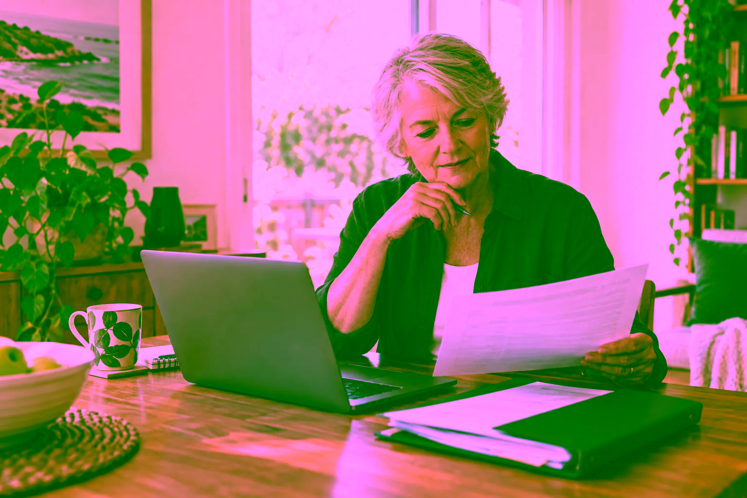 Older adult comparing a paper record with a laptop at home